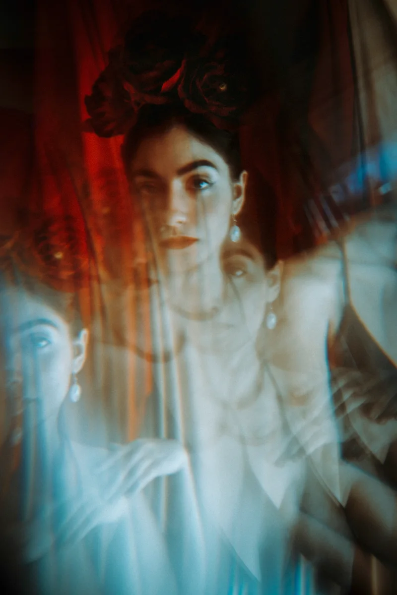 Woman in a pale blouse behind overlapping blue and orange reflections